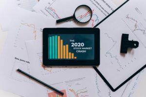 Flat lay of tablet showing 2020 stock market crash with charts and papers.
