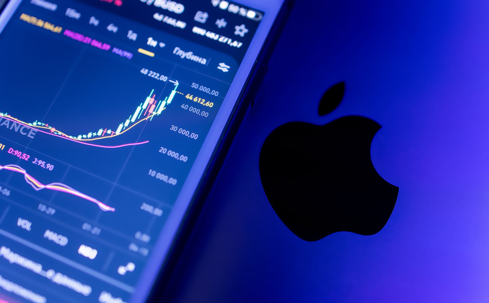 A close-up of an Apple device displaying stock market graphs, indicating economic trends.