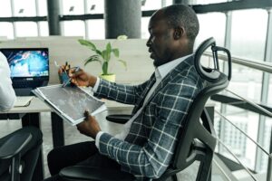 A businessman in a stylish suit reviews financial charts in a modern office setting.