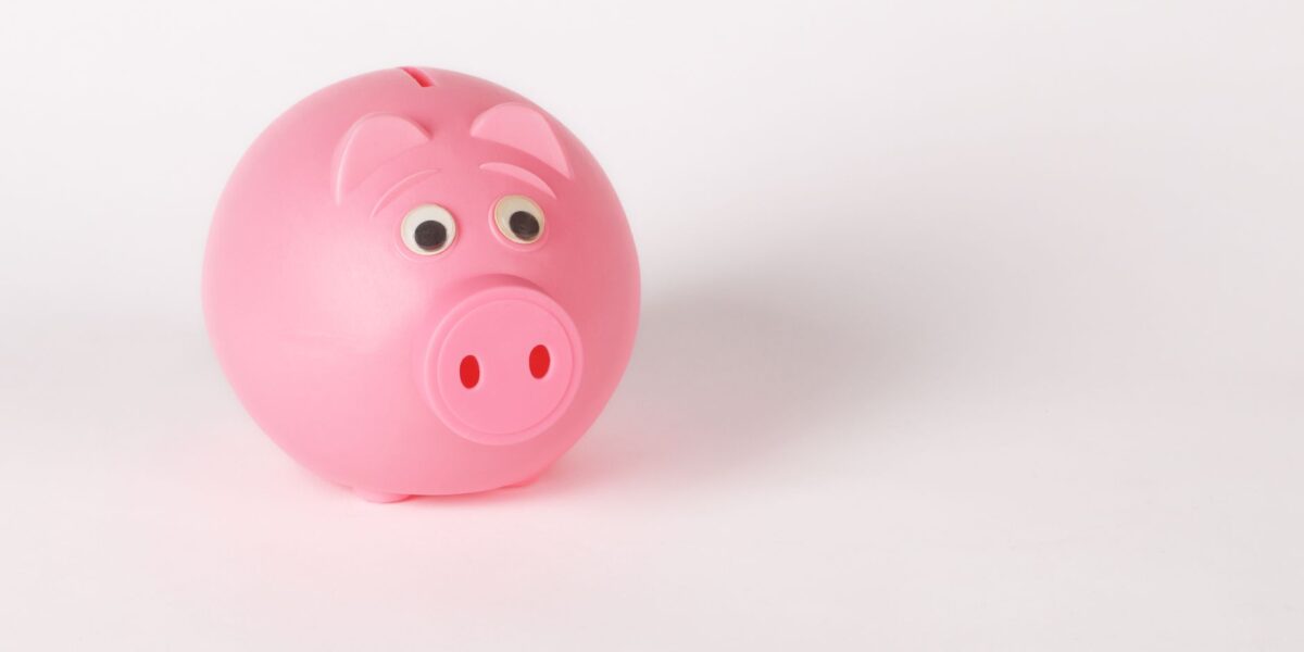 A cute pink piggy bank with googly eyes on a white background, symbolizing savings and finance.