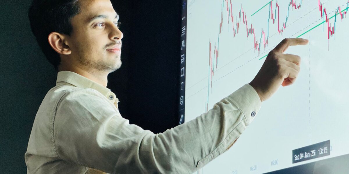 Man analyzing stock market graph on a digital board with a focused expression.