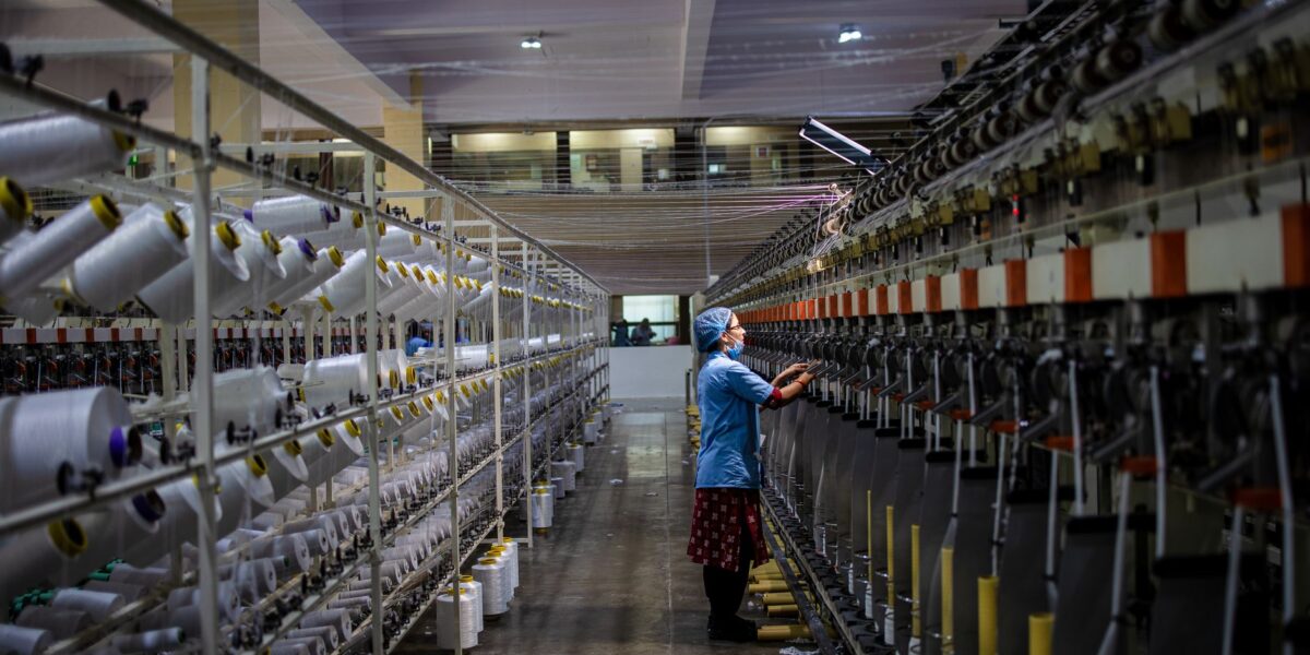 Textile factory worker monitoring machinery. Industrial and manufacturing setting.