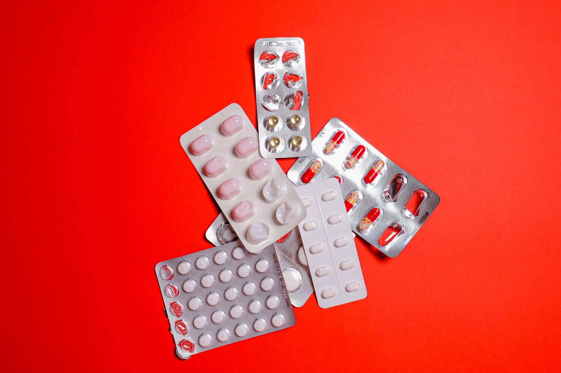 Blister packs with assorted pills over a vibrant red surface. Ideal for healthcare themes.