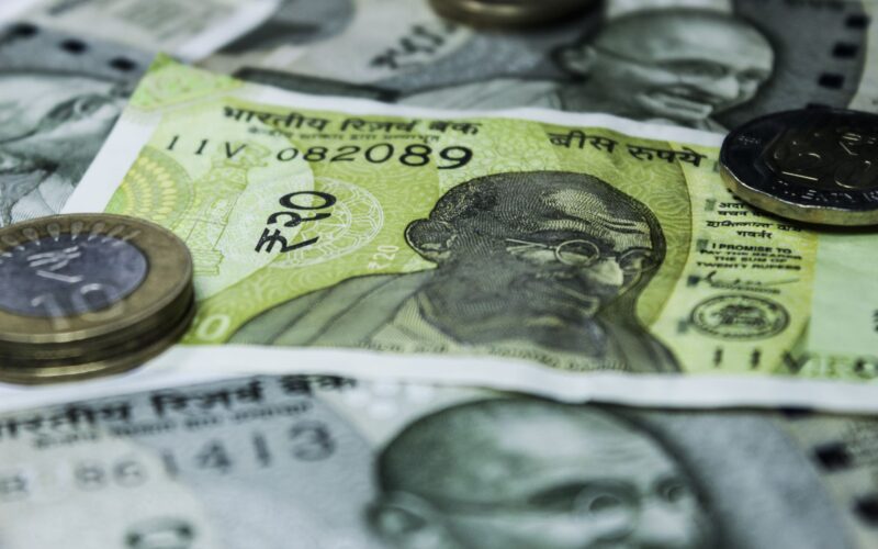 Close-up shot of Indian currency notes and coins, highlighting economic themes.
