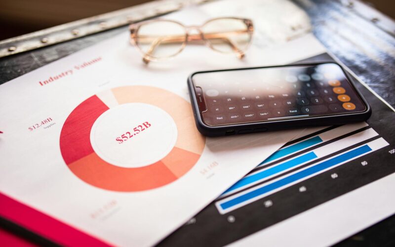 Smartphone on business documents with charts and graphs, illustrating financial analysis.