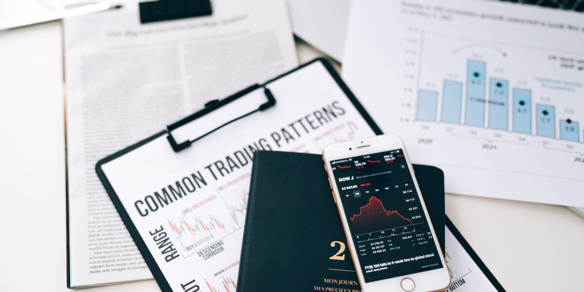 Overhead view of financial graphs and smartphone displaying stock market trends on a desk.