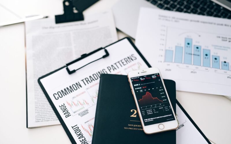 Overhead view of financial graphs and smartphone displaying stock market trends on a desk.