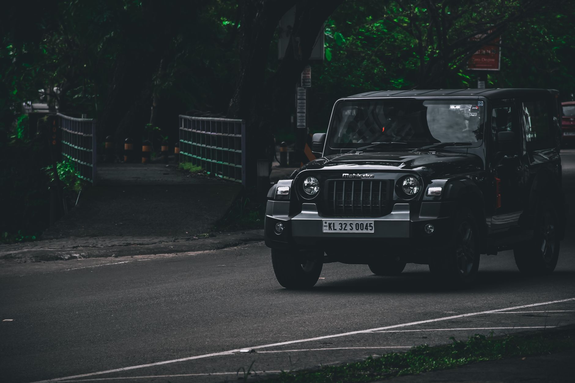 A black SUV drives down a dimly lit forest road, creating a mysterious and adventurous vibe.