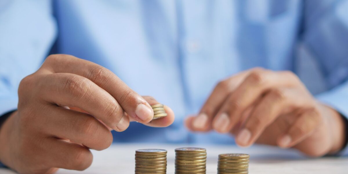 Close-up of hands stacking gold coins, symbolizing financial growth and savings.