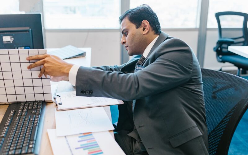 A businessman in a suit reviewing data charts at his office desk.