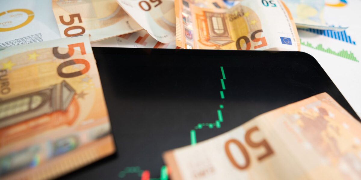 Close-up of 50 euro banknotes with a digital stock market chart on a tablet, depicting financial growth.