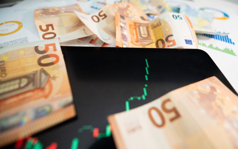 Close-up of 50 euro banknotes with a digital stock market chart on a tablet, depicting financial growth.