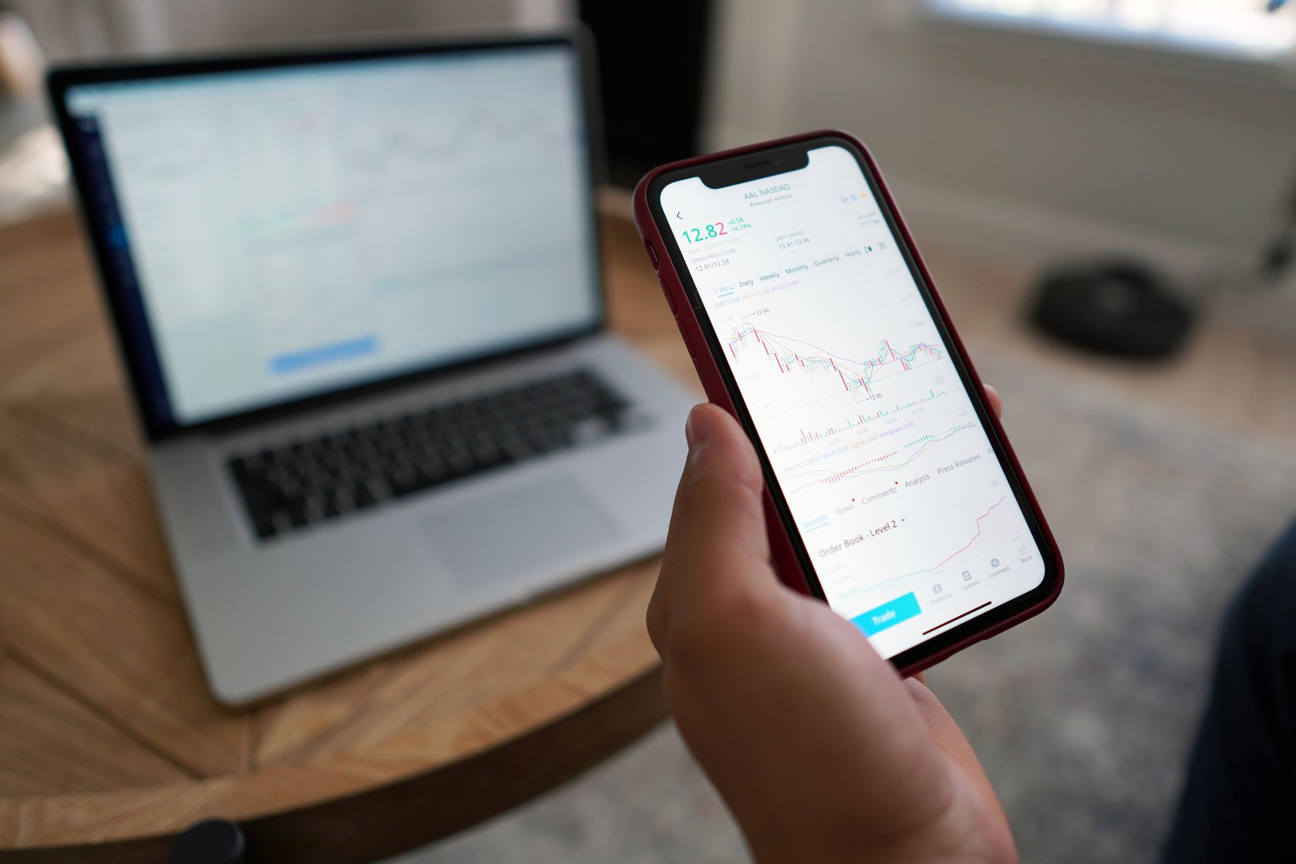 A person trading stocks on a smartphone and laptop. Ideal for finance themes.