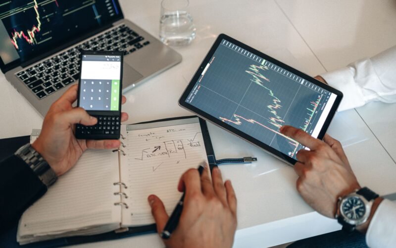 Business professionals analyzing charts on digital devices during a meeting.