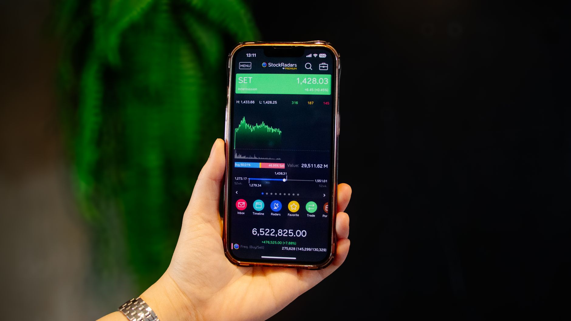 Close-up of a hand holding a smartphone displaying a stock trading app with real-time data.