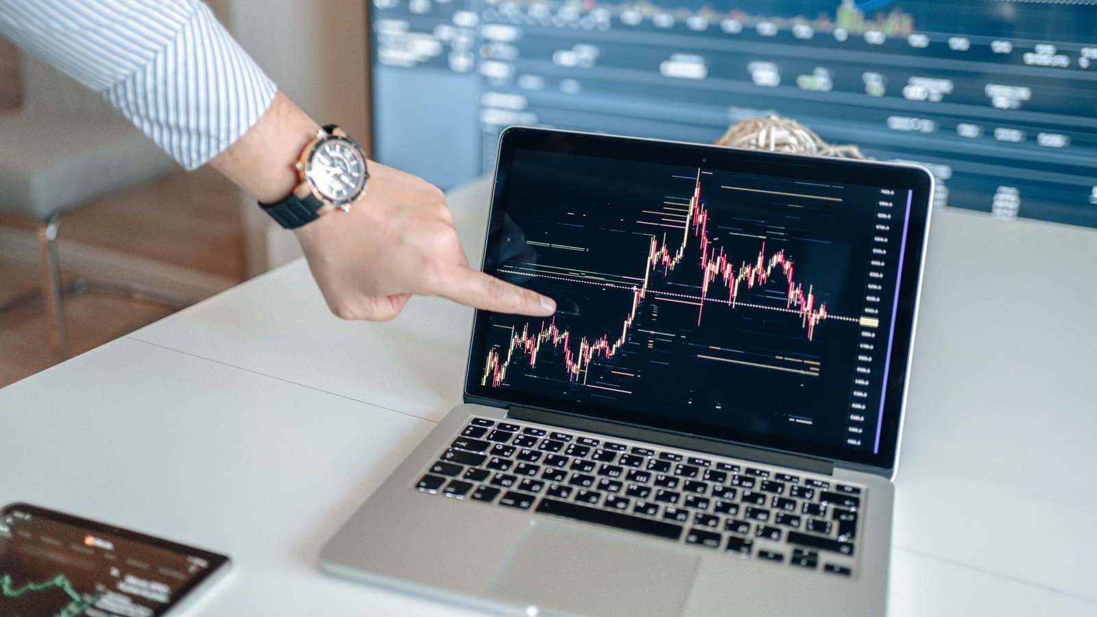 A professional examines financial graphs on a laptop, indicating market trends.