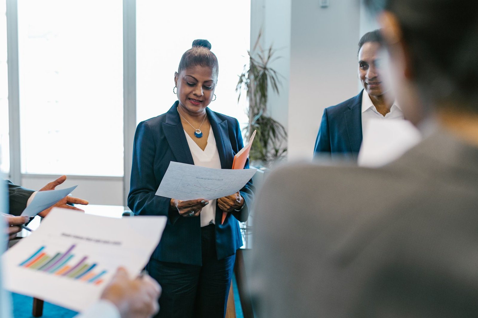 A group of professionals reviewing documents during a business meeting in a modern office setting.