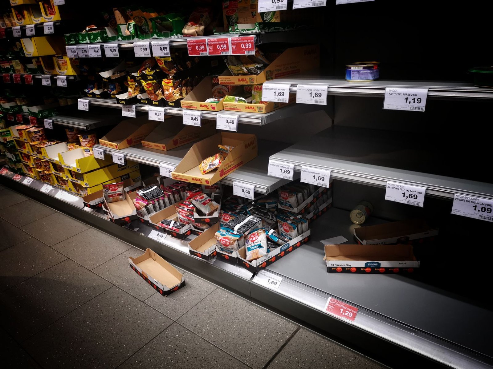 High angle of empty and full shelves in supermarket with price tags and cardboard boxes