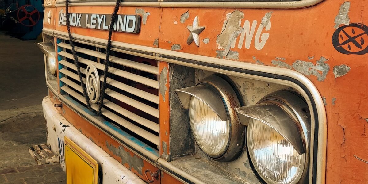 Close-up view of a rusty Indian truck front with visible headlights and peeling paint.