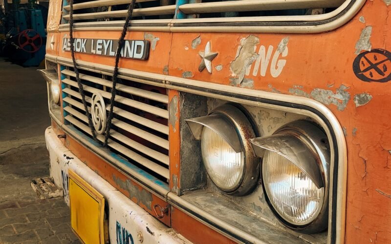 Close-up view of a rusty Indian truck front with visible headlights and peeling paint.