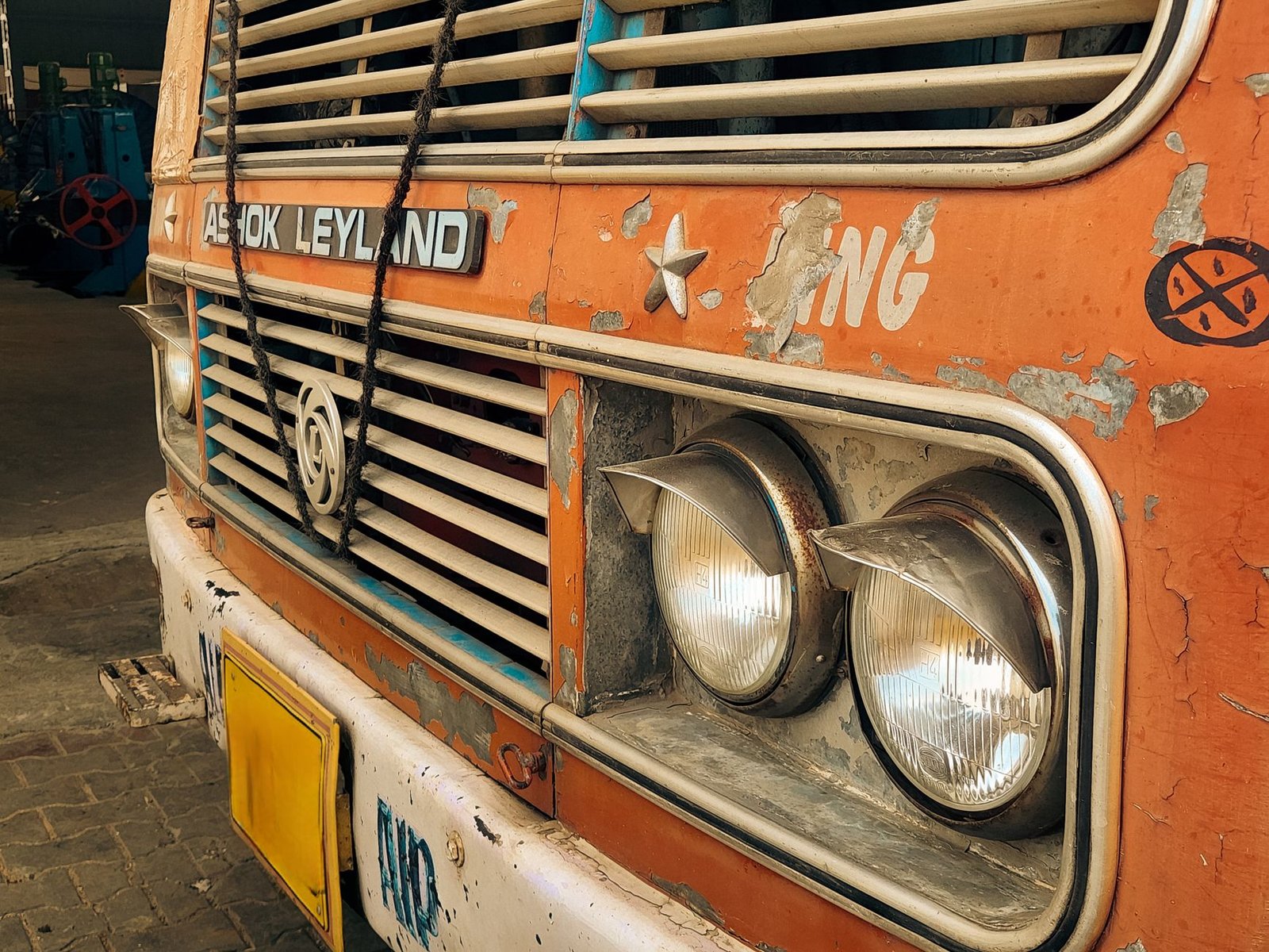 Close-up view of a rusty Indian truck front with visible headlights and peeling paint.