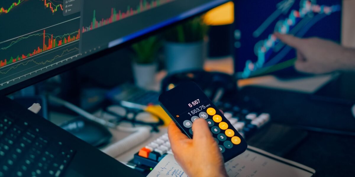 A focused shot of financial trading with screens, calculator, and data charts.