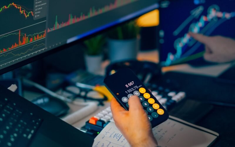A focused shot of financial trading with screens, calculator, and data charts.