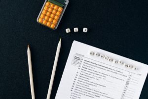 Flat lay of tax form, pencils, and calculator on black background, emphasizing tax deductions.