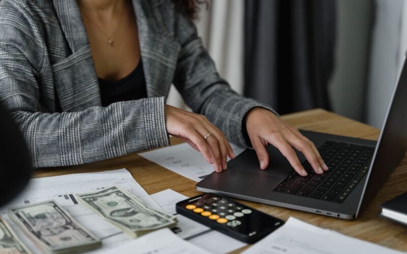 A businesswoman working on finance management with cash and calculator on desk.