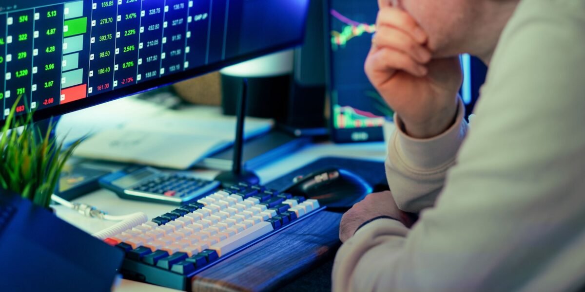A stock trader intensely analyzing financial market data displayed on multiple screens in a modern office.