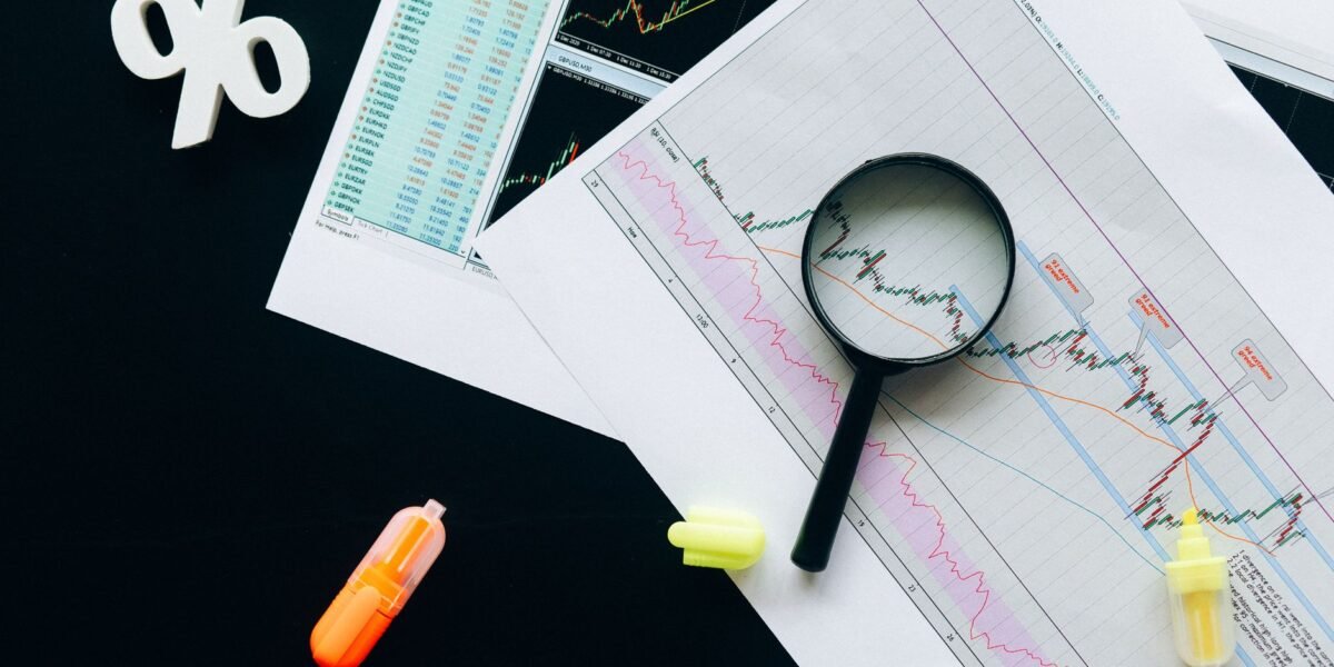 High-angle view of financial charts, showcasing stock market analysis with magnifying glass and highlighters.