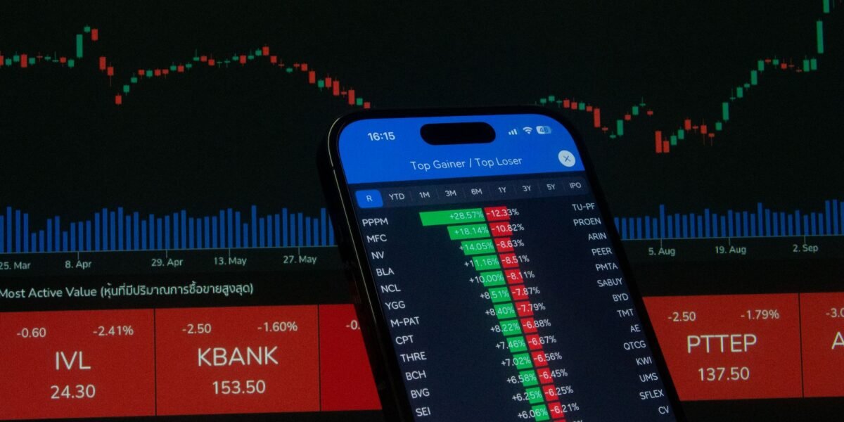 Smartphone with stock market data in front of financial chart.