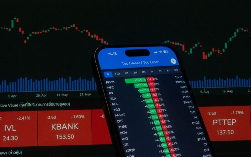 Smartphone with stock market data in front of financial chart.