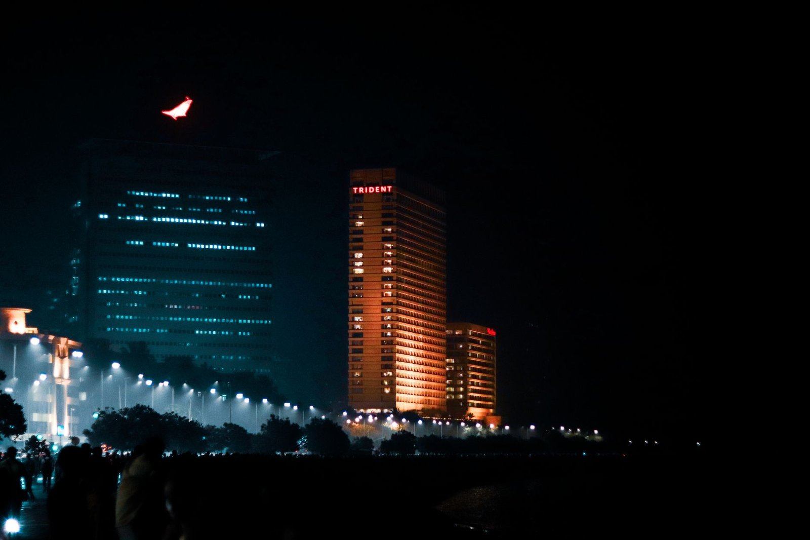 Nighttime view of the illuminated Trident Hotel in Mumbai, showcasing vibrant city lights.