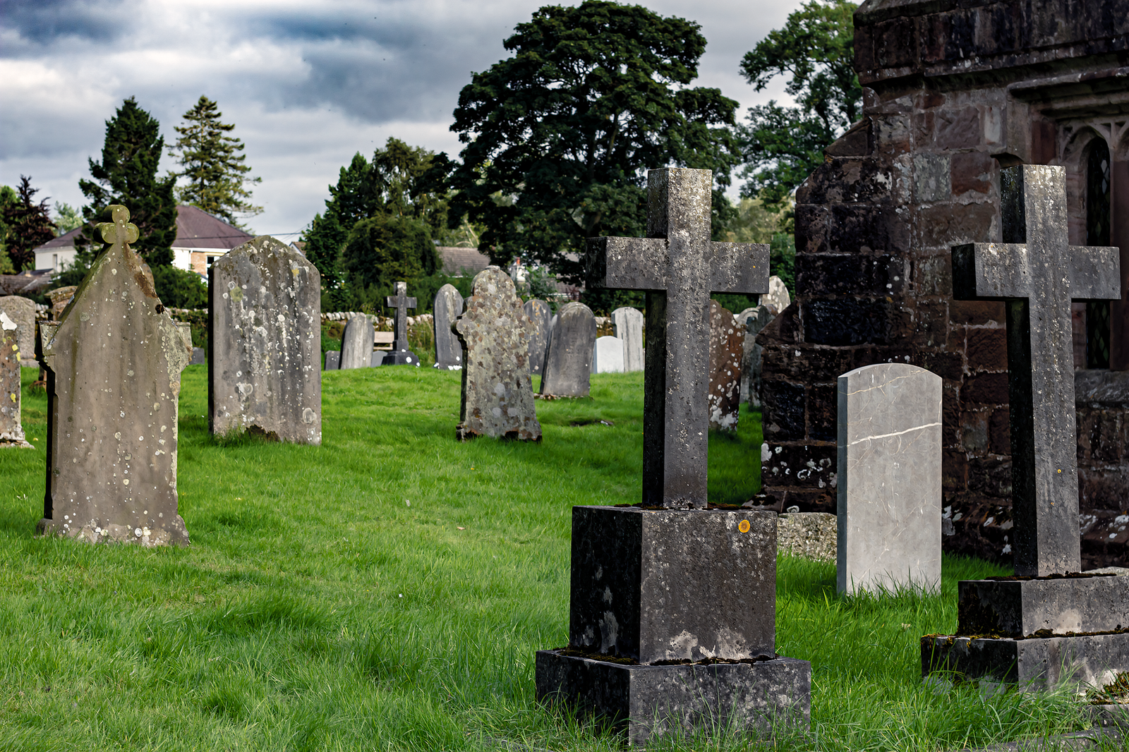 A tranquil cemetery with ancient tombstones and crosses on a lush green lawn.