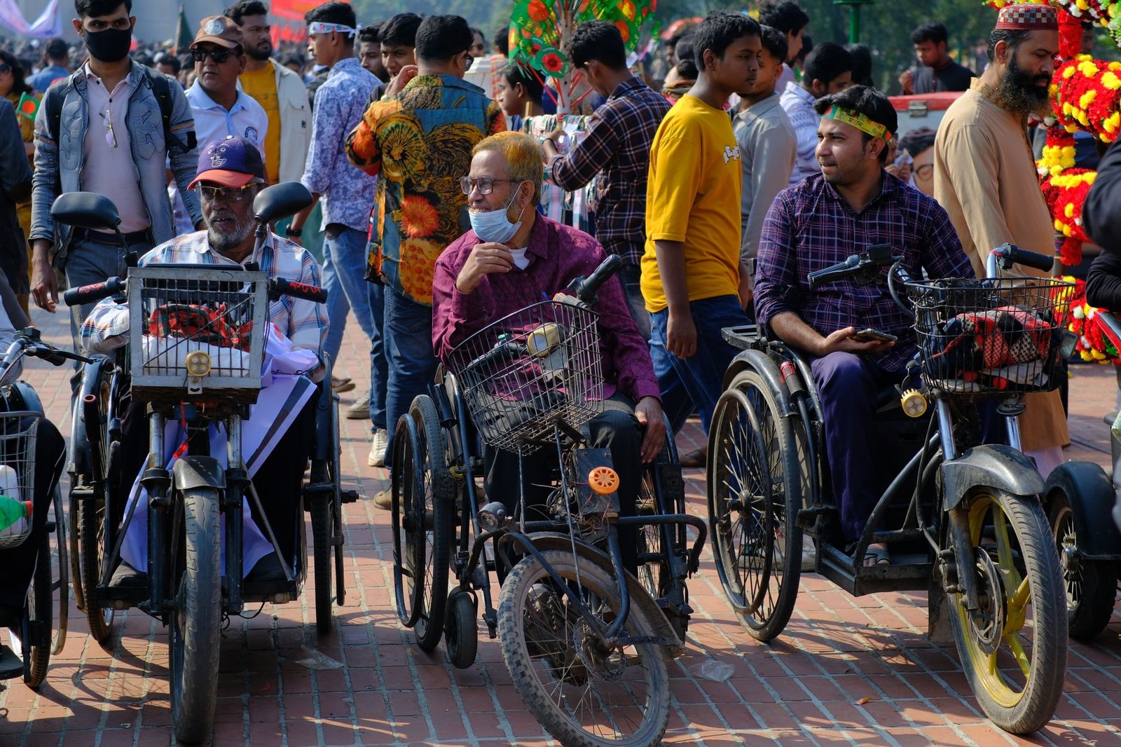 A vibrant street scene in Savar, Bangladesh featuring wheelchair users and a crowd celebrating.