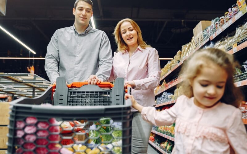 Happy family enjoying a fun shopping trip together in a supermarket aisle.