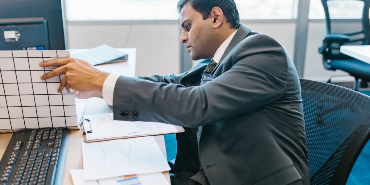 A businessman in a suit reviewing data charts at his office desk.