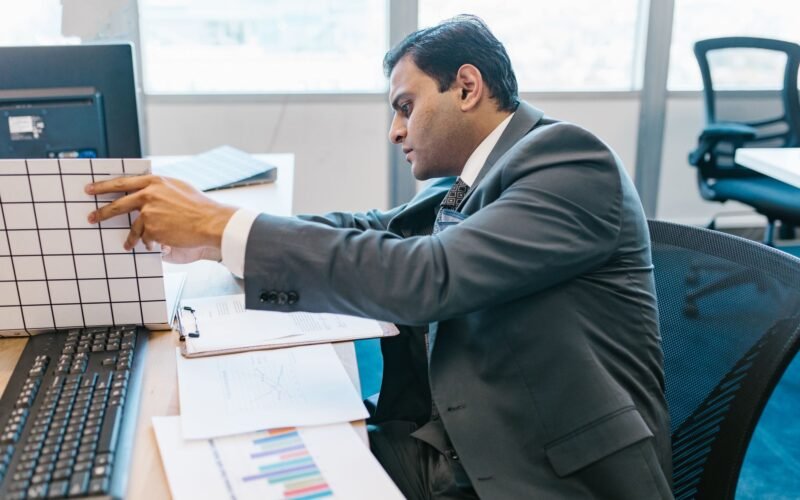 A businessman in a suit reviewing data charts at his office desk.