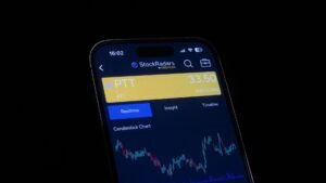 Close-up of a smartphone screen displaying a stock trading app with candlestick charts, showing real-time stock data.