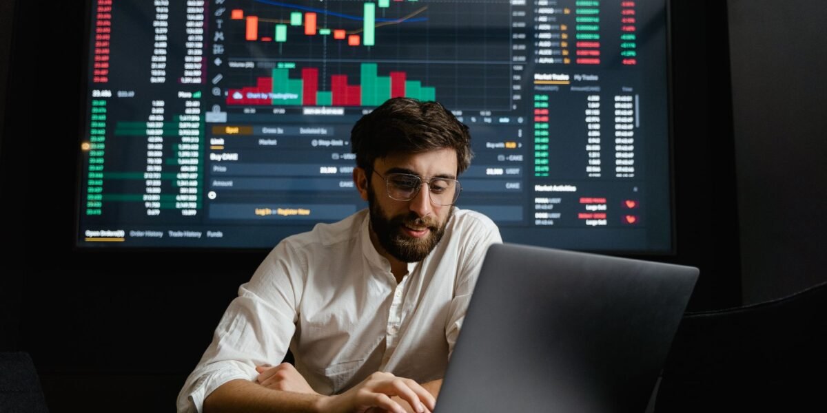 Male analyst studies cryptocurrency trends at a workstation with multiple displays showing market data.