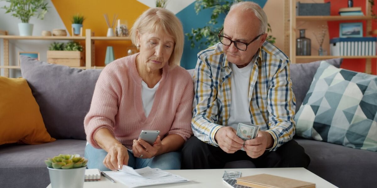 Senior couple managing household finances in cozy living room setting.