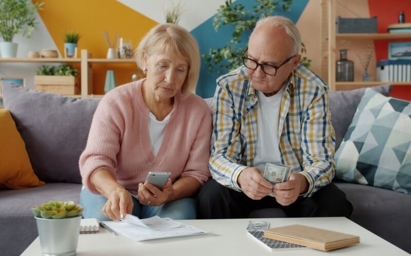 Senior couple managing household finances in cozy living room setting.