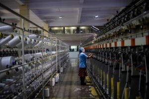 Textile factory worker monitoring machinery. Industrial and manufacturing setting.