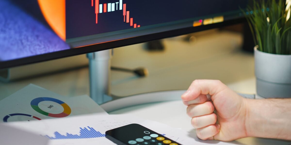Close-up of a desk with financial graphs, a calculator, and a fist symbolizing determination.
