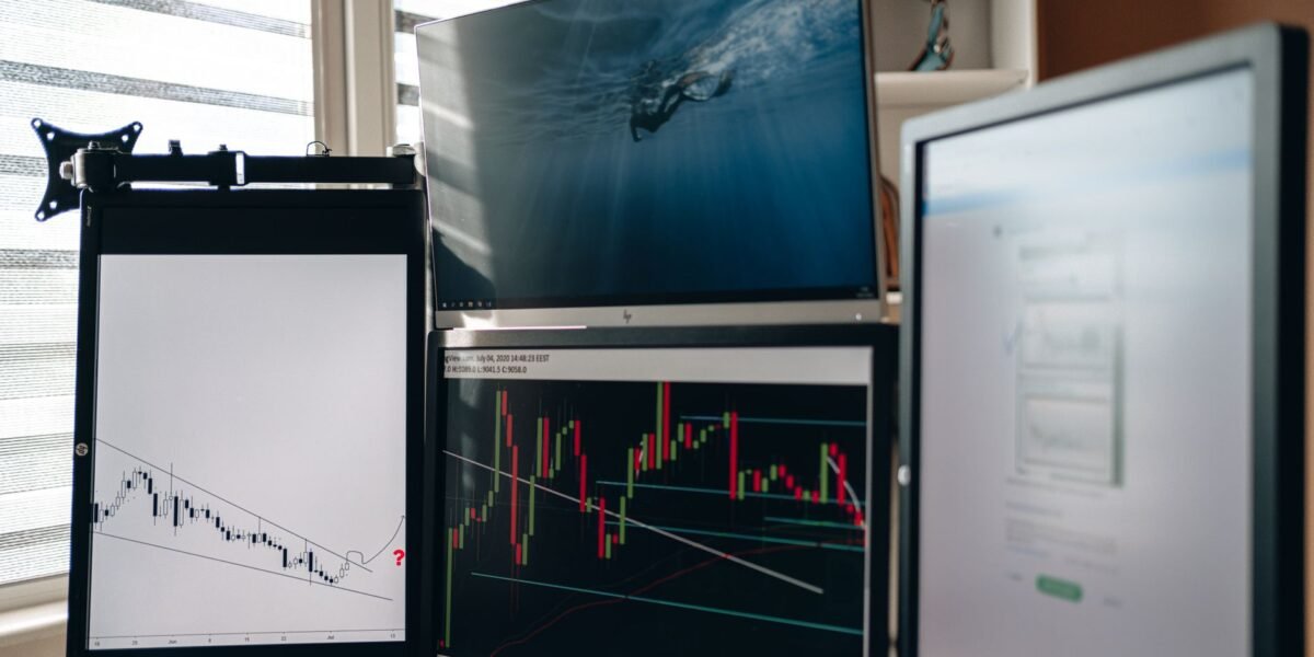 A home office setup featuring multiple monitors displaying trading charts and data analysis.