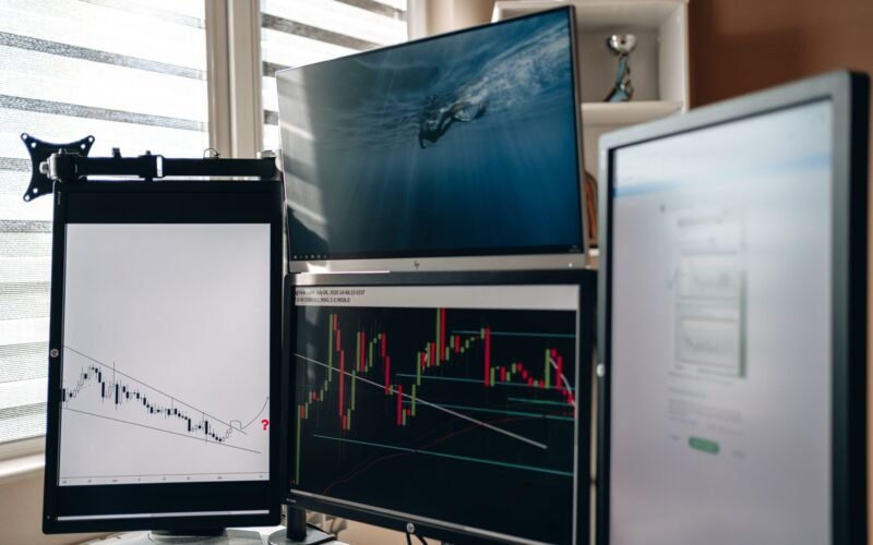 A home office setup featuring multiple monitors displaying trading charts and data analysis.