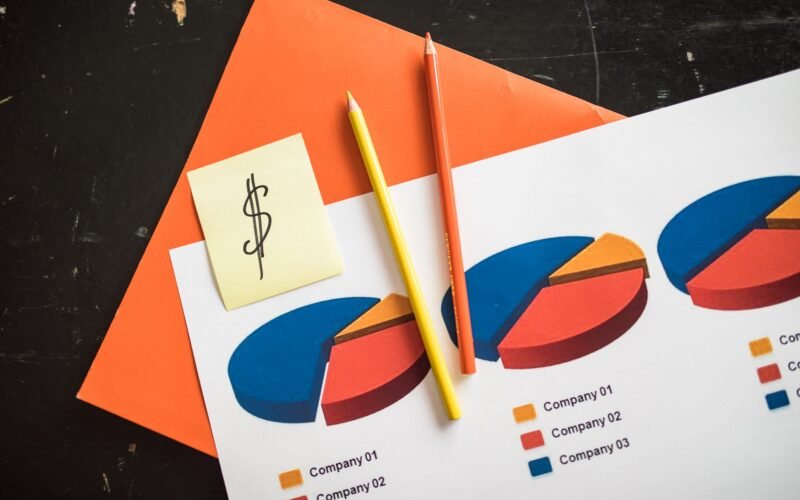 A creative arrangement of financial pie charts with colorful pencils and a dollar note, perfect for business themes.