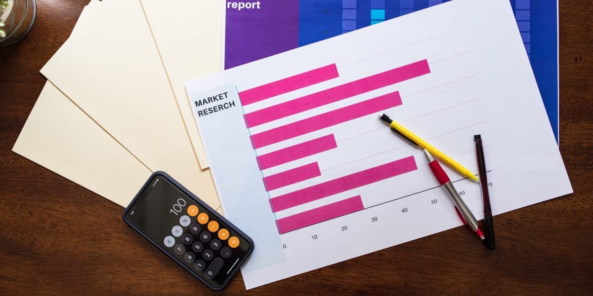 Top view of market research reports and calculator on a wooden desk, illustrating business analysis.