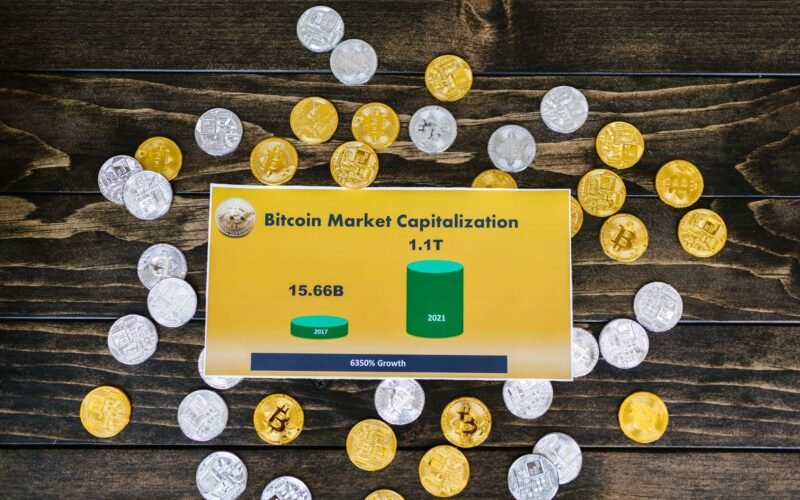 Bitcoin coins on wooden surface with chart showing market cap growth to 1.1T.